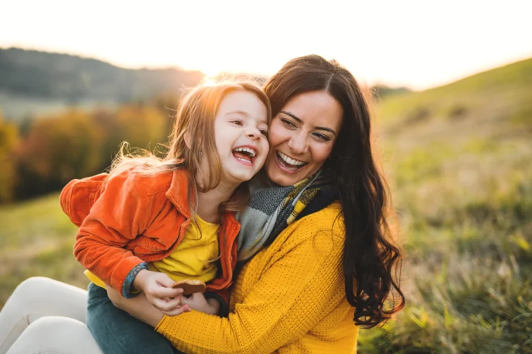 Mother and daughter laughing together outside